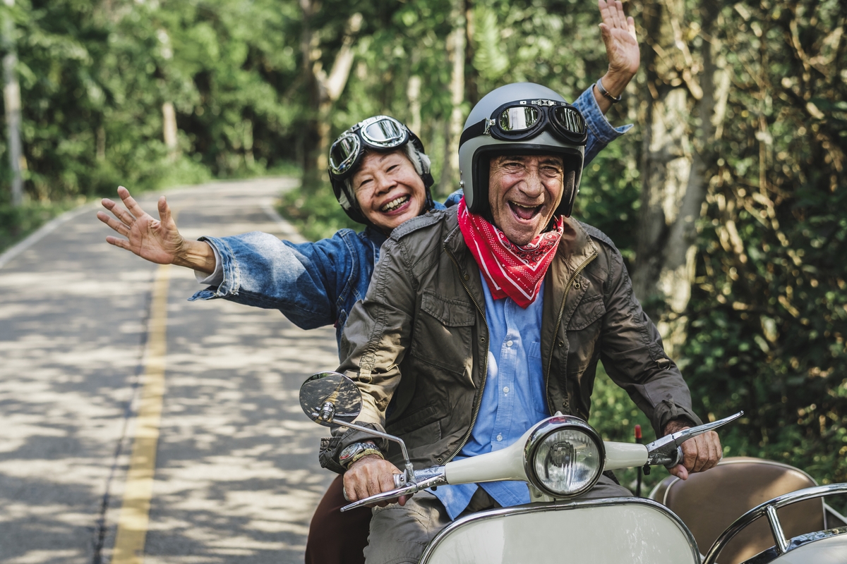 Senior couple enjoying scooter ride, vivid tone